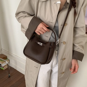Close-up of litchi pattern leather texture and silver clasp on a dark coffee bucket bag