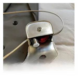 Detail view of silver mini crossbody bag showing red lining and internal storage space
