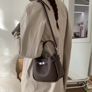 Detailed view of dark brown pebbled leather bucket bag with silver metal lock closure