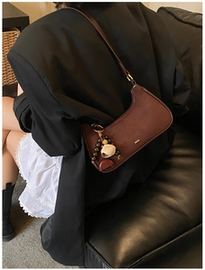 Detail view of burgundy suede half-moon bag with retro beaded pendant and metal accents