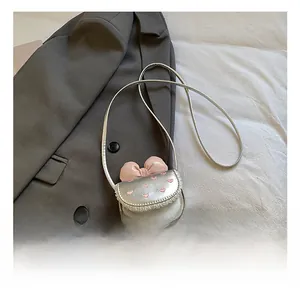 Close-up of silver child's mini bag with pink bow and embroidered heart detail