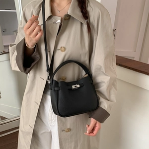 Detail of black pebbled leather bucket bag with silver turn-lock and crossbody strap