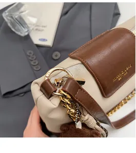 Detail of color-block quilted bag with gold chain strap and brown teddy bear charm