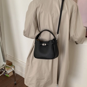Detail of black lychee grain leather bucket bag with silver twist lock and shoulder strap
