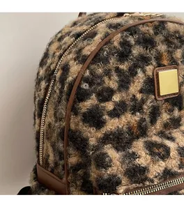 Macro shot of leopard print plush fabric with brown leather trim and golden hardware