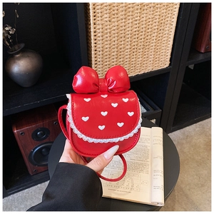 Detail of red crossbody bag featuring large bow, white hearts, and delicate lace trim