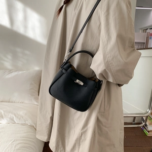 Detail of black pebbled leather bucket bag with silver turn-lock and adjustable strap