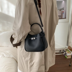 Detail of black lychee grain leather bucket bag with silver metal buckle on a model