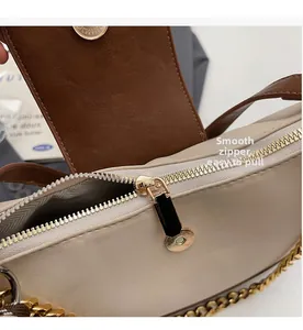 Close-up of smooth gold zipper and metallic chain on a retro beige leather handbag