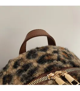 Detail of leopard print faux fur backpack with brown leather handle and gold zippers