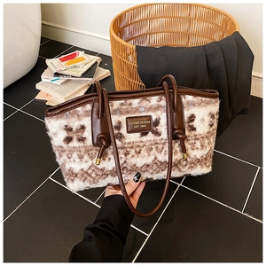 Close-up of plush geometric tote bag with brown faux leather trim and brand logo patch