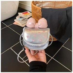 Close-up of a silver handbag featuring a pink bow, lace trim, and heart embroidery