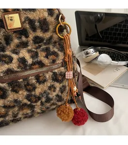 Detail of leopard print plush backpack with gold zipper and stylish pom-pom pendant