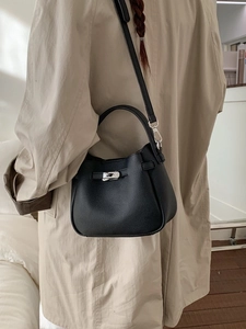Fashionable black pebbled leather bucket bag with silver metal buckle on a model