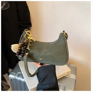 Detail of dark green hobo bag with vintage gold hardware and peanut charm on luggage