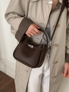 Fashionable dark coffee pebbled leather bucket bag with silver hardware on a city street