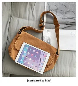 Brown canvas crossbody bag size comparison with an iPad on a soft grey fabric