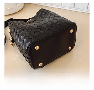 Vue détaillée du sac seau en cuir tressé noir avec quatre clous de protection en métal doré
