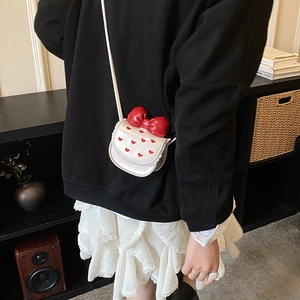 Close-up of white mini crossbody bag featuring red heart prints and a large red bow detail