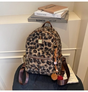 Close-up of fluffy leopard print backpack featuring golden hardware and plush ball charm