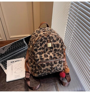 Detail of leopard print faux fur backpack with golden logo and colorful pompom charms
