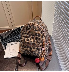 Detail of leopard print faux fur backpack with leather trim and decorative plush charms
