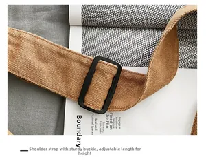 Detail view of brown canvas shoulder strap with a black plastic adjustable buckle