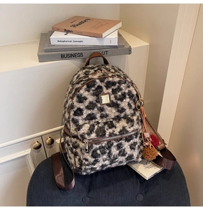 Close-up of leopard print plush backpack showing fuzzy texture and cute fur ball charm