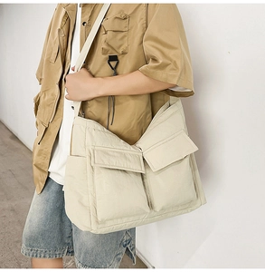 Side view of large beige canvas tote bag with flap pockets on minimalist model