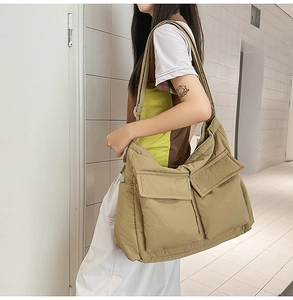 Detail of large khaki utility tote bag with front flap pockets and durable texture