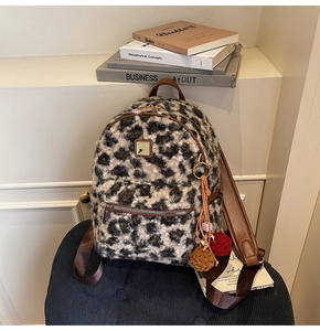Detailed macro view of soft faux fur leopard print texture and zipper with plush pom-poms