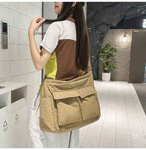 Detail of khaki nylon crossbody bag showing dual large pockets and adjustable strap