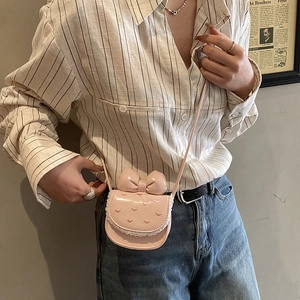 Detail of pink bow handbag featuring lace edges and heart embroidery worn as crossbody