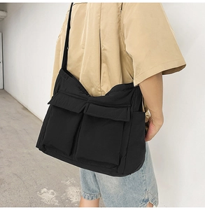 Side view of black padded crossbody tote bag with large utility pockets worn by model