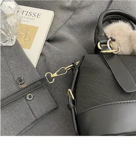Detail of woven texture on black retro bag with gold metal hook and plush charm