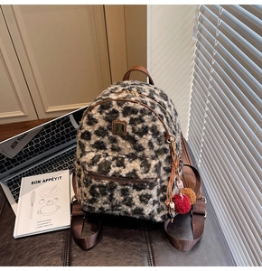 Detail of leopard print plush backpack showing soft faux fur texture and brown leather strap