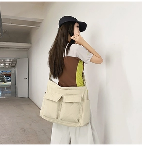 Detail of off-white large capacity tote bag with front flap pockets for daily commute
