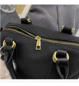 Close-up of black woven leather handbag showing smooth gold zipper and refined craftsmanship
