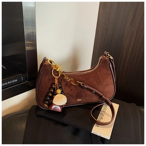 Detail of hobo bag in dark brown suede and leather with artistic bead pendant charm