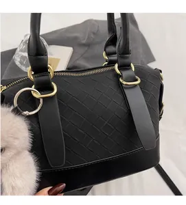 Close-up of black woven leather handbag with gold zipper and gray plush charm detail