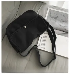 Detail of minimalist black canvas messenger bag with silver buckle on a lifestyle background
