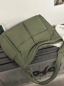 Army green nylon tote bag with dual front pockets and wide strap in an urban style