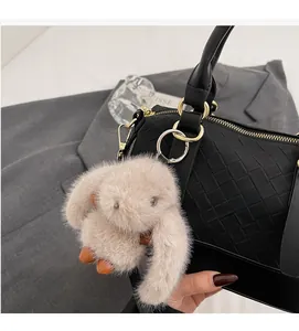 Detail of black woven leather handbag with gold hardware and plush bunny charm