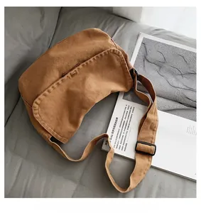 Detail view of adjustable canvas shoulder strap and metal buckle on brown messenger bag