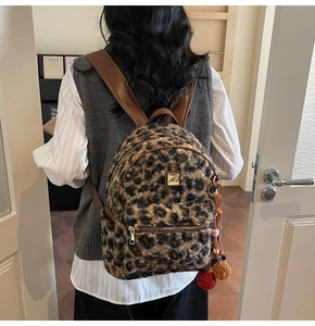 Detail of leopard print plush backpack with soft faux fur texture and colorful pom-poms