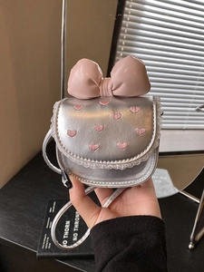 Silver leather handbag with pink heart embroidery and large bow, shown in hand