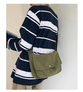 Detail view of olive green canvas messenger bag with adjustable strap and flap closure