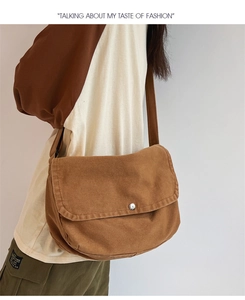 Brown canvas messenger bag with silver metal buckle styled on a fashion model