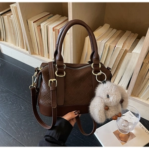 Detail der braunen Vintage-Tasche mit Webstruktur, Wildleder-Einsätzen und Plüsch-Anhänger