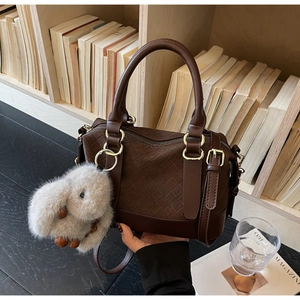 Nahaufnahme der braunen Vintage-Henkeltasche mit Webmuster und Plüsch-Hasenanhänger